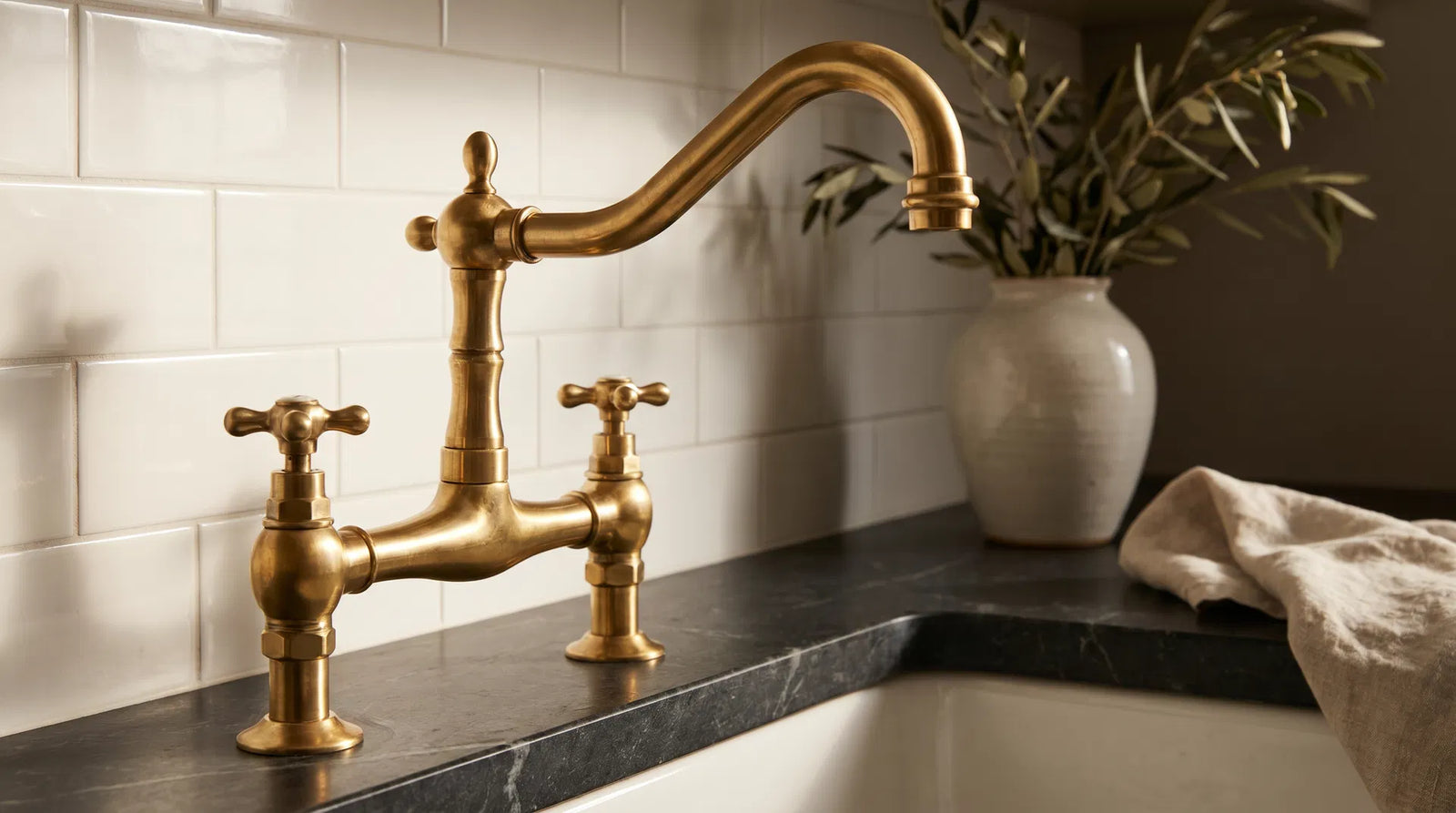 Classic unlacquered brass bridge faucet on dark soapstone countertop